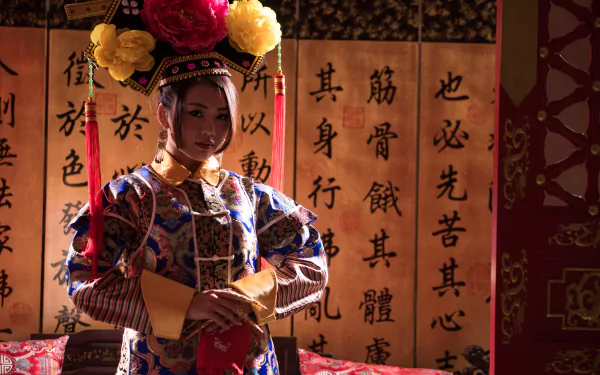 A Taiwanese woman dressed in traditional Chinese costume, portraying Qián Fūrén, set against a background of ancient calligraphy scrolls in this 4K Ultra HD desktop wallpaper.