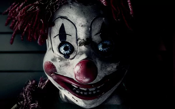 Close-up of a cracked, sinister clown doll with chipped paint, red nose and glassy blue eyes — Poltergeist (2015) movie HD PC desktop wallpaper/background.