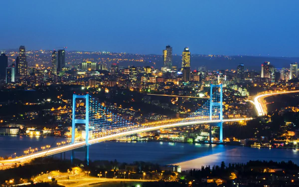 A stunning night view of Istanbul's Bosphorus Bridge illuminated against the skyline, showcasing the vibrant city lights and the beauty of Turkey's Bosphorus Strait.