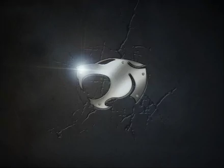 Metal Thundercats (1985) TV show emblem embossed on a cracked dark surface with a bright lens flare — HD PC desktop wallpaper.