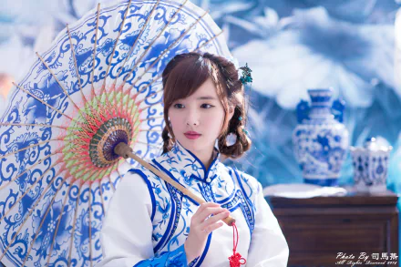 Woman model in traditional blue-and-white costume holding an ornate umbrella beside porcelain vases — 4K Ultra HD desktop wallpaper.