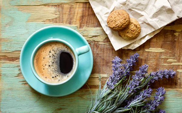 A top view of a coffee cup on a turquoise saucer, accompanied by two cookies on brown paper and a bunch of lavender, captured in 8K Ultra HD for a PC desktop wallpaper.