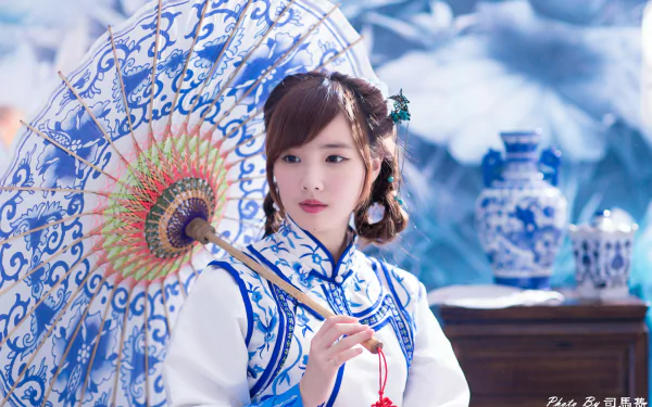 Woman model in traditional blue-and-white costume holding an ornate umbrella beside porcelain vases — 4K Ultra HD desktop wallpaper.
