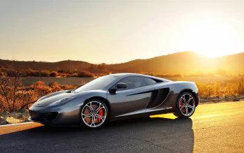 Silver McLaren MP4-12C supercar parked on a road at sunset, with a desert landscape in the background, captured in HD for a desktop wallpaper.
