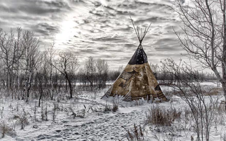 HD PC desktop wallpaper and background: a man-made tipi stands in a snowy field among bare trees beneath a dramatic, cloud-filled sky.