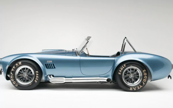 Blue Shelby AC Cobra roadster side profile with chrome side pipes and roll bar on a clean gray background — HD PC desktop wallpaper