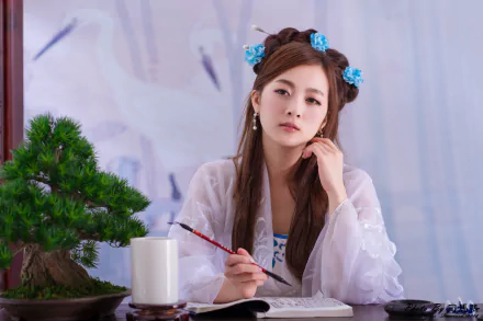A woman in traditional Chinese costume, adorned with floral hairpins, sits at a table with a bonsai and brush, deep in thought, adding elegance to this 4K Ultra HD background.