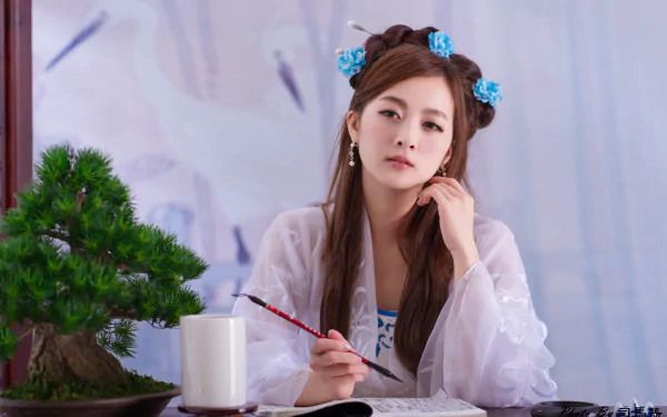 A woman in traditional Chinese costume, adorned with floral hairpins, sits at a table with a bonsai and brush, deep in thought, adding elegance to this 4K Ultra HD background.