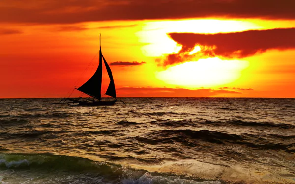 A sailing boat glides across the ocean at sunset, with vibrant orange clouds and sun illuminating the sea in this 4K Ultra HD nature landscape wallpaper.