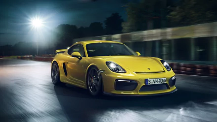 Yellow Porsche Cayman GT4 sports car speeding on a wet road at night, captured in a dynamic HD desktop wallpaper.