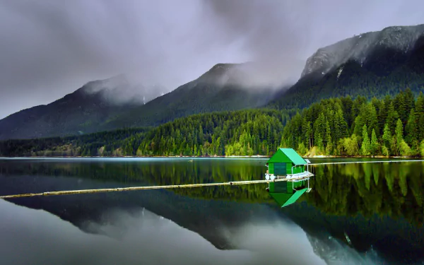 A tranquil view of Capilano Lake in Canada, surrounded by lush forests and mountains, featuring a green floating cabin reflecting in the calm waters, captured in stunning 4K Ultra HD.