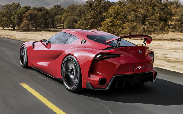 Red Toyota FT-1 concept supercar speeding on a road, captured in a 4K Ultra HD PC desktop wallpaper showcasing its sleek design and aerodynamic features.