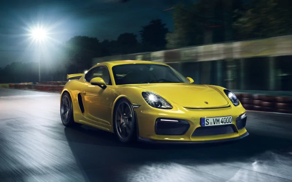 Yellow Porsche Cayman GT4 sports car speeding on a wet road at night, captured in a dynamic HD desktop wallpaper.