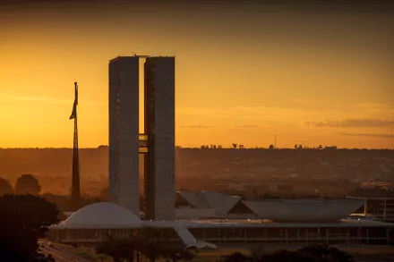 Sunrise over Brasília's modernist National Congress towers and domes, bathed in golden light — HD desktop wallpaper.