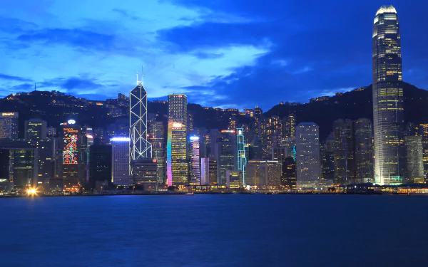 Twilight view of Hong Kong's megapolis skyline with illuminated skyscrapers against a deep blue sky, captured in 4K Ultra HD.