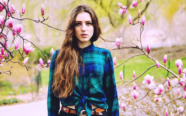 A serene image of Birdy, the English singer, surrounded by blooming magnolia flowers, capturing a blend of nature and music in a vibrant display.