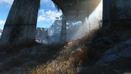 A captivating HD wallpaper from Fallout 4, showcasing a sunlit scene beneath a weathered overpass, with wild grass and urban ruins in the background.