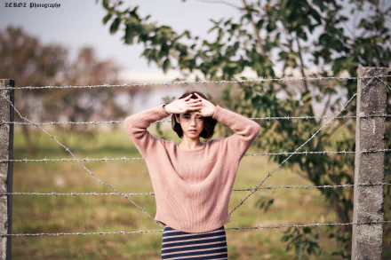 HD wallpaper featuring Taiwanese model Lín Yǔ posing behind barbed wire with a soft bokeh background in a natural outdoor setting.