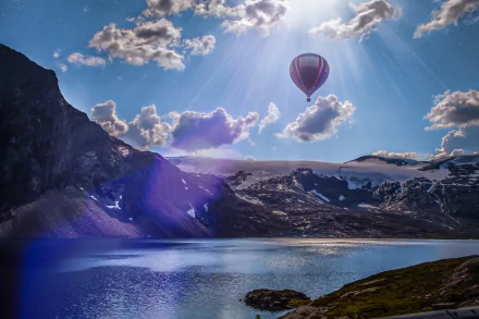 A hot air balloon floats over a serene Norwegian lake surrounded by mountains under bright sunshine and scattered clouds, captured in stunning 4K Ultra HD.