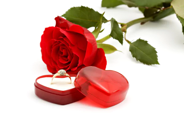 A vibrant red rose next to a heart-shaped ring box, showcasing a sparkling engagement ring. This romantic image captures the essence of love in exquisite detail.