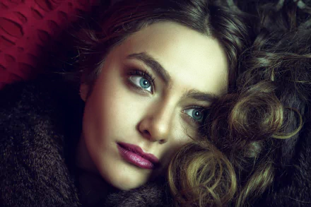 Close-up 4K Ultra HD portrait of a brunette woman with blue eyes and bold lipstick, showcasing her face with soft lighting and detailed texture.