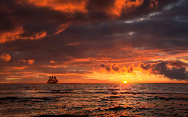 4K Ultra HD PC desktop wallpaper: silhouetted sailing ship on the horizon at a fiery red-orange sunset, dramatic clouds glowing above a rippling ocean.
