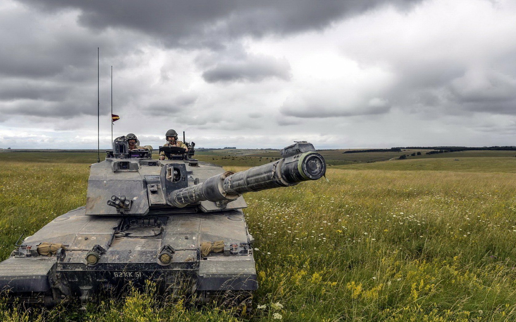 HD PC desktop wallpaper background: Challenger 2 main battle tank in a grassy field beneath dramatic cloudy sky, military scene.