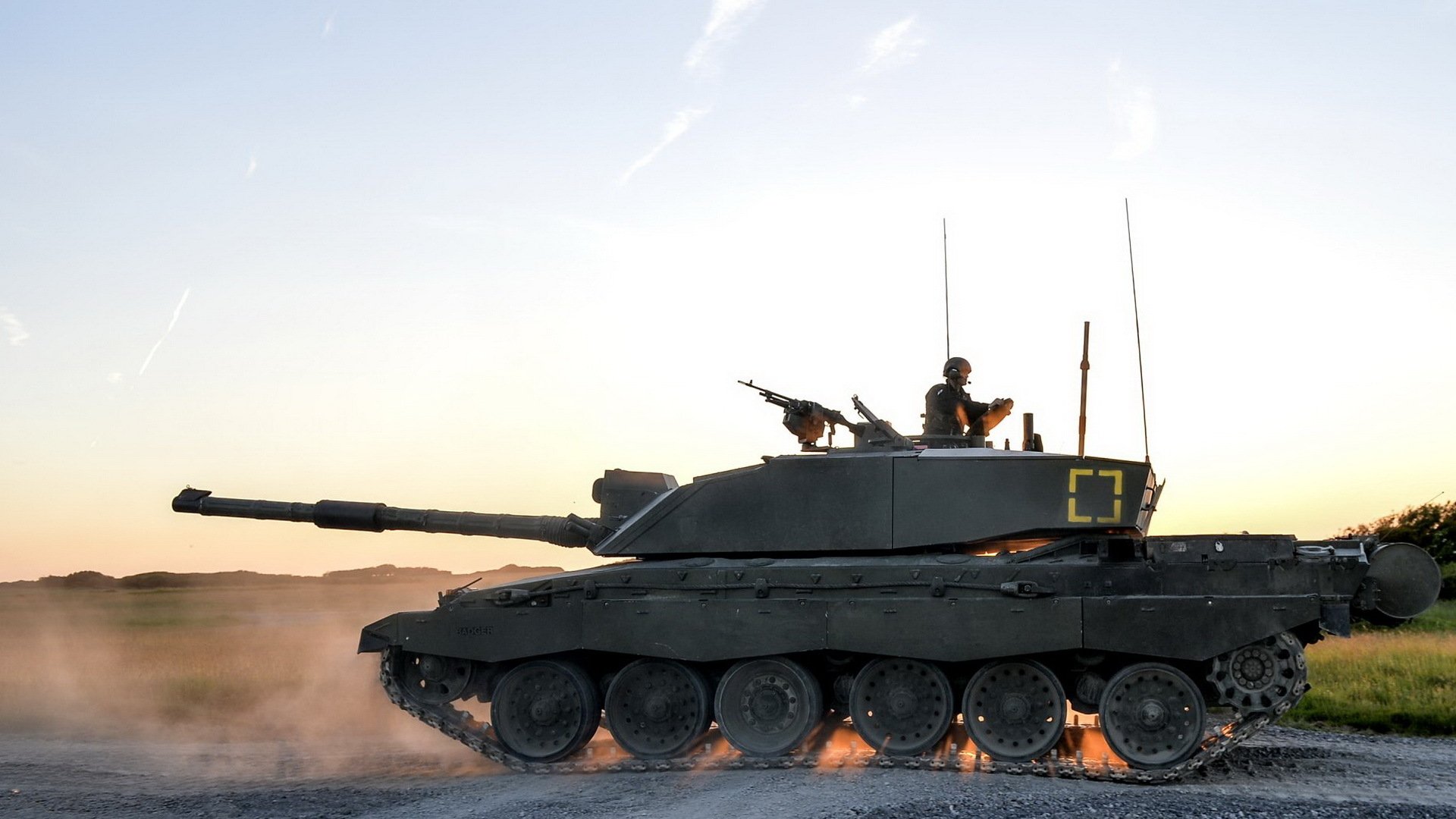 HD desktop wallpaper featuring a Challenger 2 military tank moving across a dusty terrain at sunset.