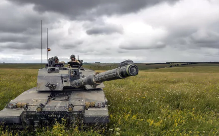 HD PC desktop wallpaper background: Challenger 2 main battle tank in a grassy field beneath dramatic cloudy sky, military scene.