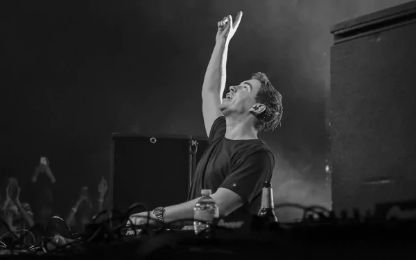 A monochrome image of DJ Hardwell, Robbert van de Corput, passionately performing with one arm raised, capturing the energy of his music in a striking black and white style.