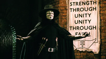 A striking HD wallpaper featuring the iconic character V from *V for Vendetta*, standing confidently with arms outstretched against a brick wall, embodying themes of unity and resistance.