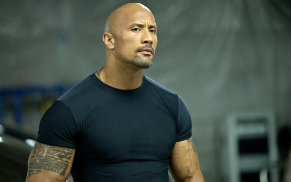 HD desktop wallpaper: muscular bald actor in a black tee, intense expression on an industrial set, evoking the action movie San Andreas.