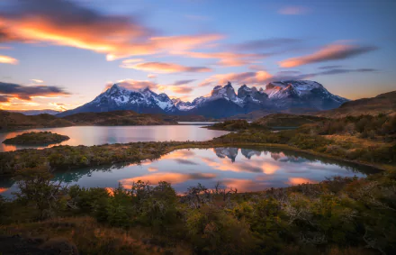 A stunning landscape of Torres del Paine in Chile, featuring dramatic mountains and a tranquil lake reflecting the colorful sky, showcasing the natural beauty of Patagonia.