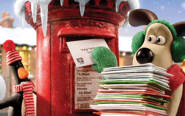 HD PC desktop wallpaper featuring Wallace & Gromit’s Gromit wearing earmuffs and green mittens, posting letters in a snowy red mailbox with a festive penguin nearby.