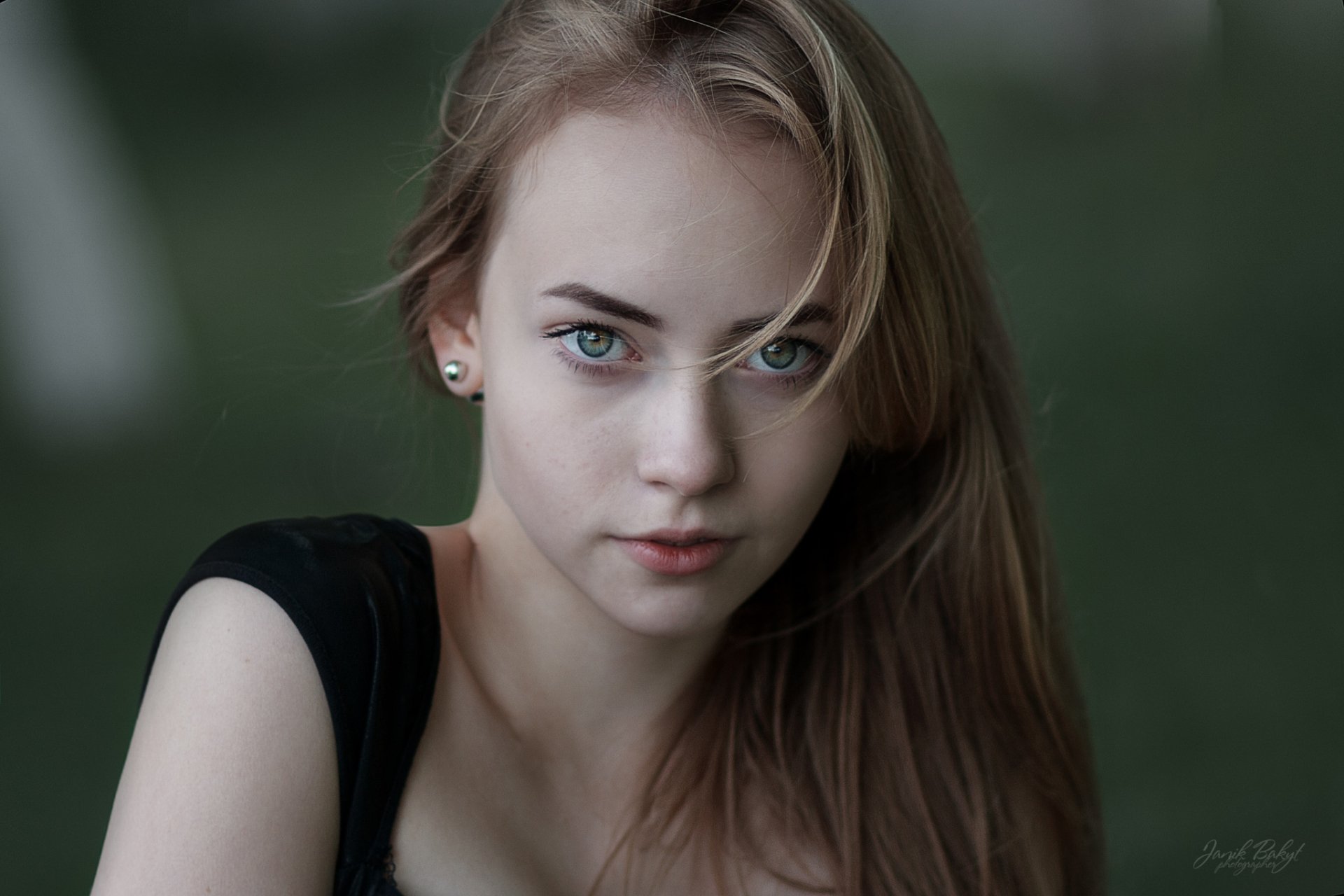 Close-up of a blonde woman with green eyes and earrings, set against a soft bokeh background, captured in HD for a PC desktop wallpaper.
