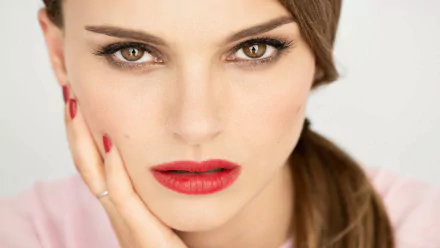 Close-up of Natalie Portman with striking brown eyes and bold red lips, showcasing elegance and beauty. This HD wallpaper captures her captivating presence.