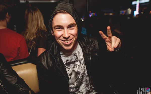 HD PC desktop wallpaper featuring Hardwell smiling and flashing a peace sign at a music event.