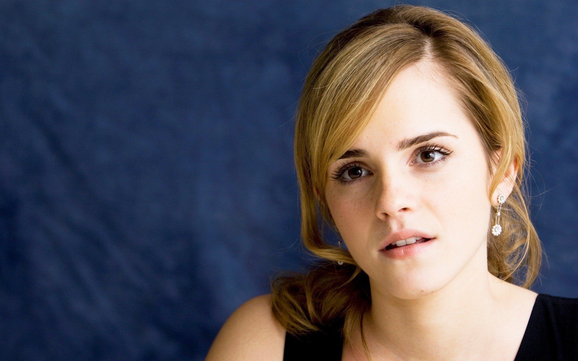 HD desktop wallpaper featuring a close-up of celebrity Emma Watson against a dark blue textured background.