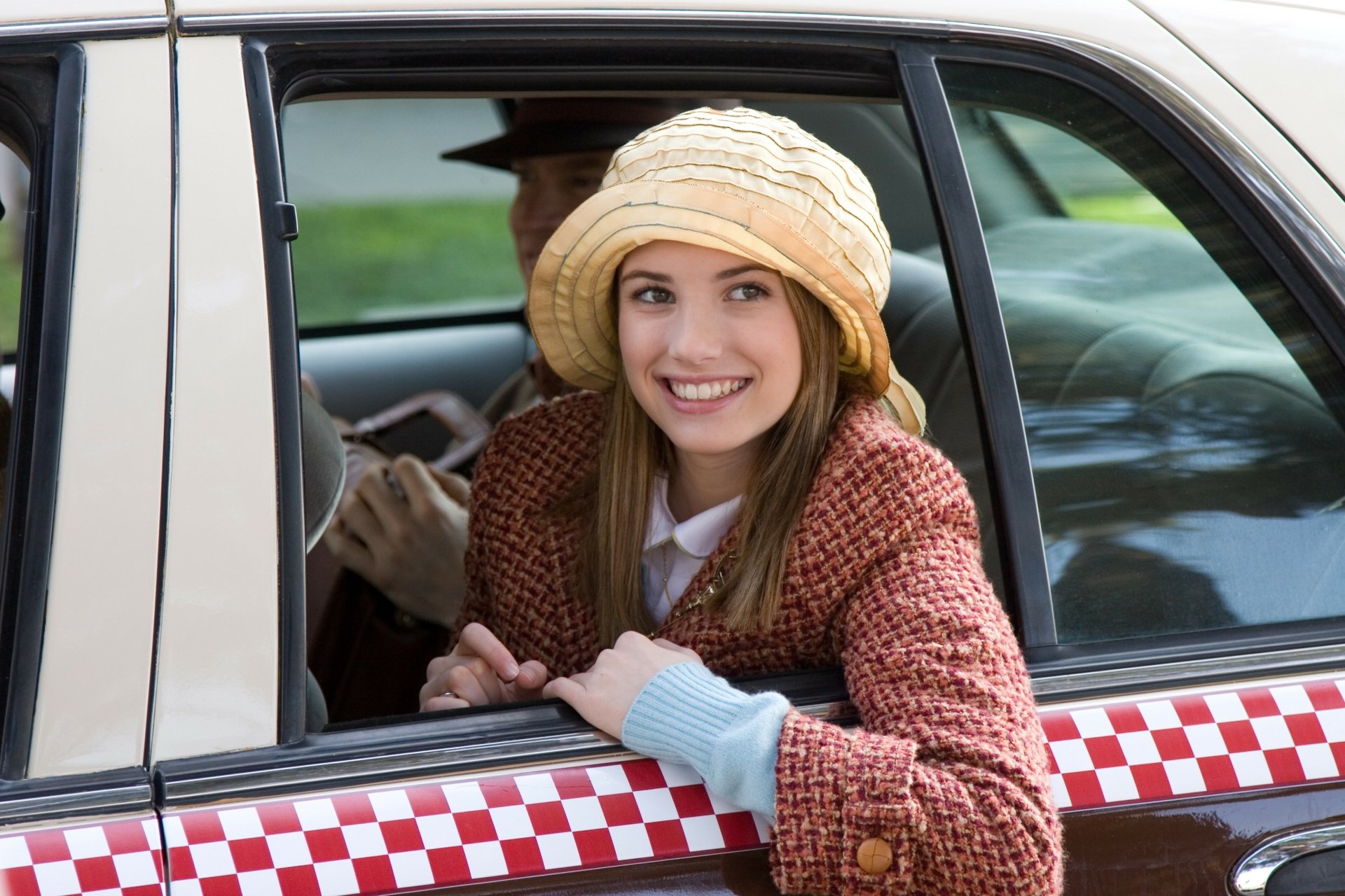 2K Quad HD desktop wallpaper: smiling young woman in a vintage hat leaning from a checker‑pattern taxi window, scene from the Nancy Drew movie.