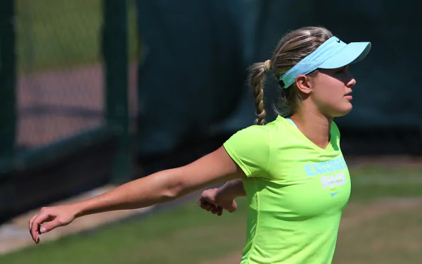 Eugenie Bouchard stretches on a tennis court wearing a bright green shirt and visor, captured in a vibrant 4K Ultra HD sports desktop wallpaper.