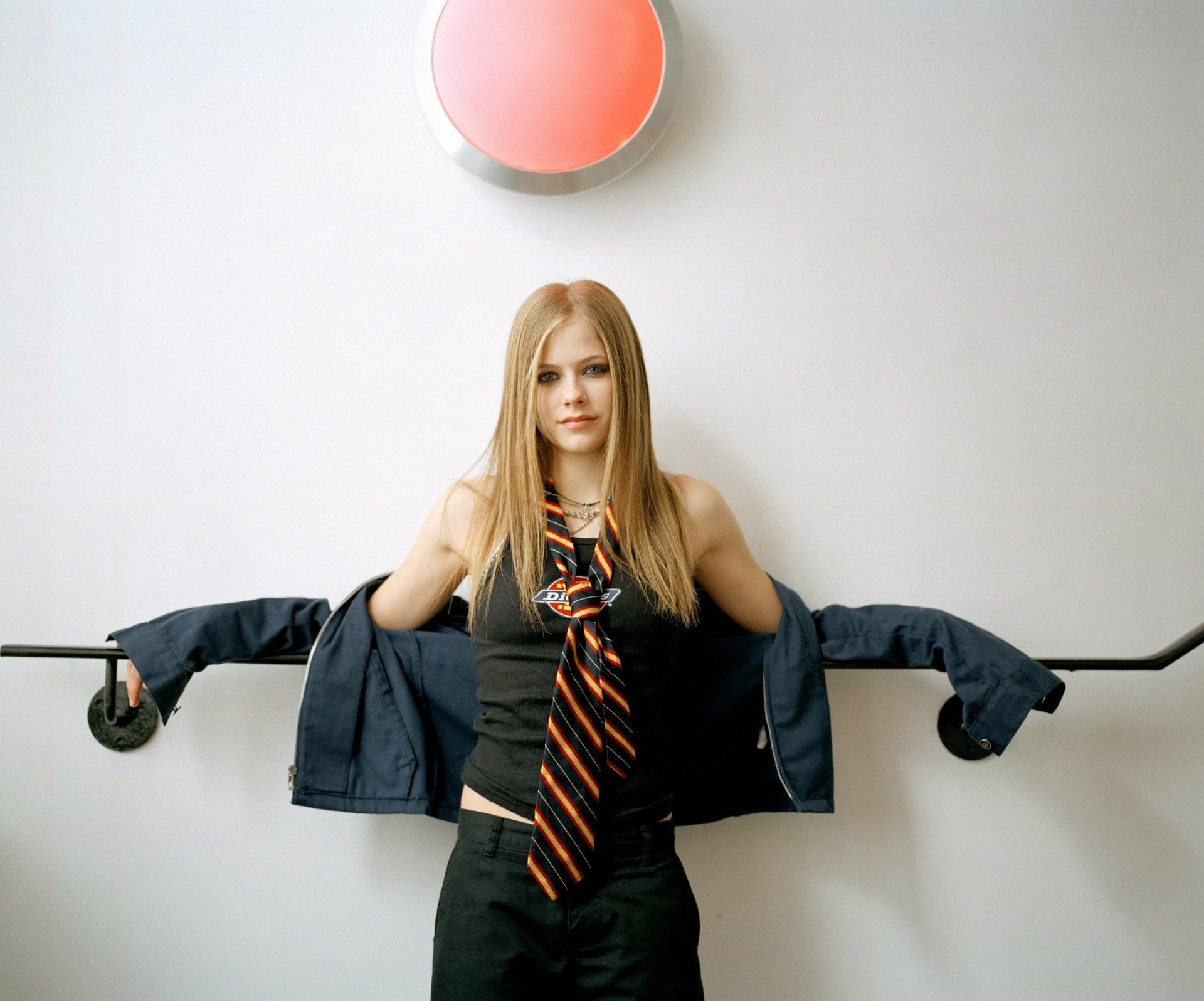 4K Ultra HD PC wallpaper featuring Avril Lavigne in a black outfit with an orange-striped tie, posing against a plain white background with music-themed styling.
