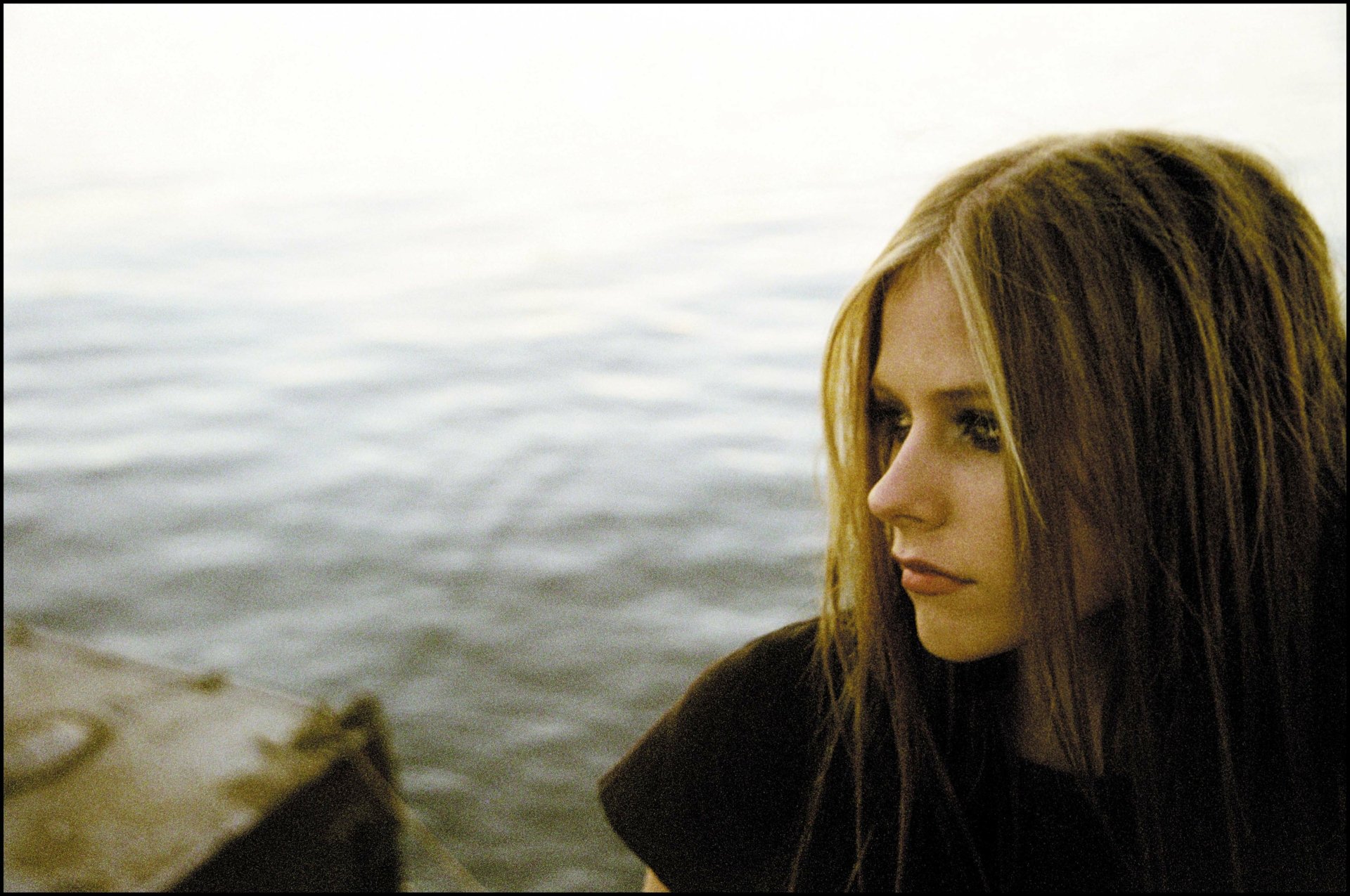 4K Ultra HD PC desktop wallpaper featuring a close-up of Avril Lavigne by the water, capturing a contemplative mood with soft natural lighting.