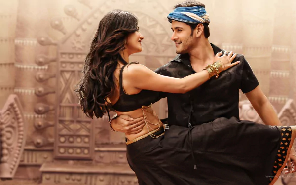 Mahesh Babu and Shruti Haasan dance together in a vibrant scene from the movie Srimanthudu, set against a colorful backdrop, creating a captivating HD wallpaper.