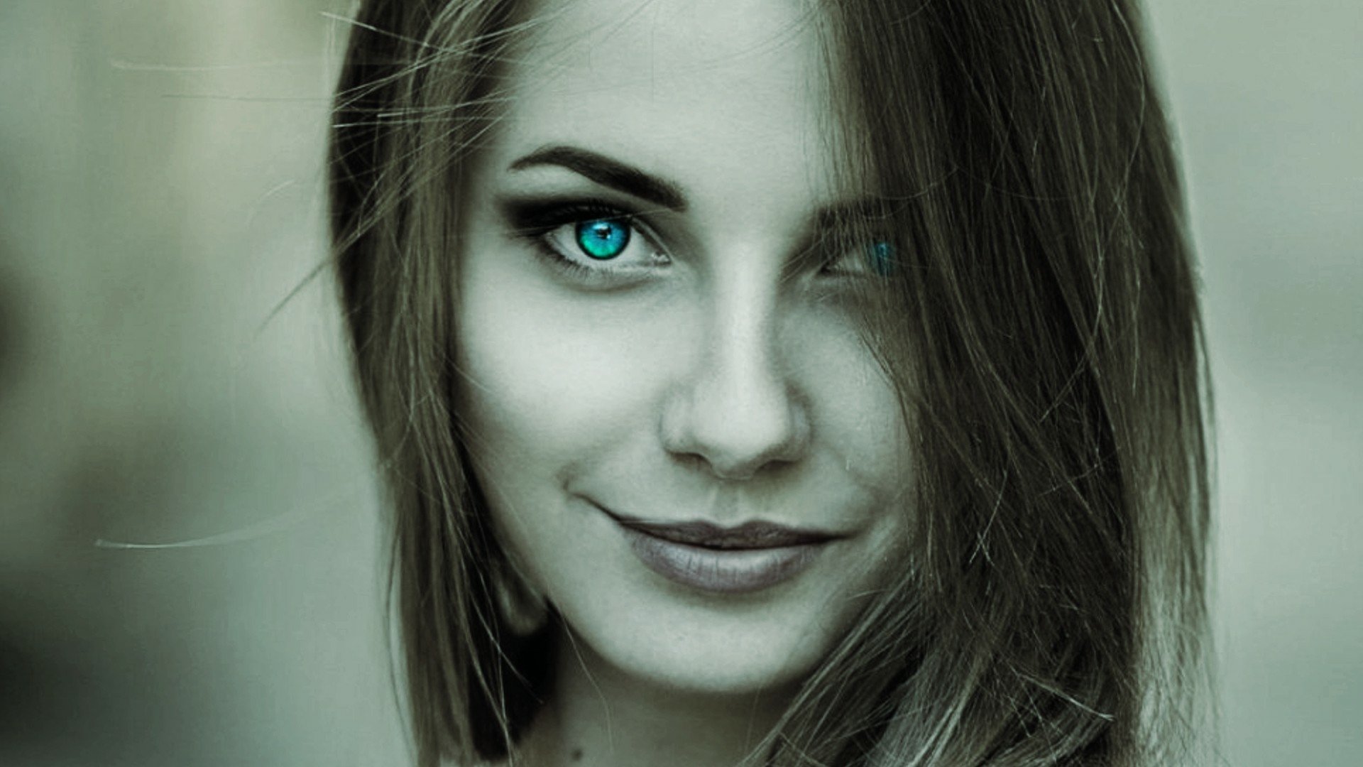 HD PC desktop wallpaper: close-up portrait of a woman with striking teal eyes and a subtle smile against a soft green-gray background.