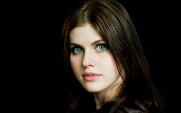 HD desktop wallpaper featuring actress Alexandra Daddario with black hair and blue eyes against a dark background.