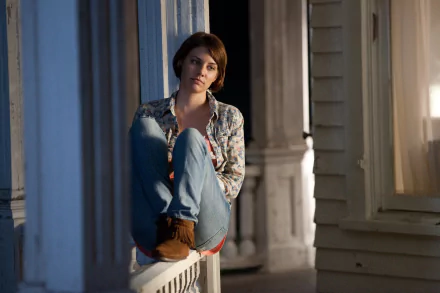 A scene featuring Lauren Cohan from the TV show The Walking Dead, sitting on a porch railing in a thoughtful pose, creating a striking HD desktop wallpaper.