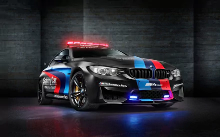 A striking BMW M4 Safety Car features bold blue and red graphics, illuminated lights, and a sleek design, set against a dramatic dark background, perfect for an HD desktop wallpaper.