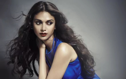 Elegantly poised Aditi Rao Hydari in a blue outfit against a soft gray background, captured in a high-definition desktop wallpaper.