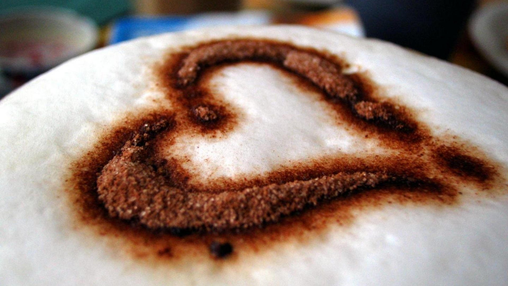 A close-up of a heart shape made with cocoa powder on creamy coffee foam, creating a warm and inviting food-themed wallpaper for your desktop.