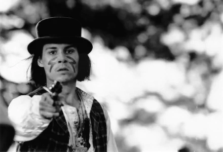 Black-and-white 2K Quad HD PC wallpaper/background: a man in a period hat and face paint points a pistol, cinematic scene from the movie Dead Man.